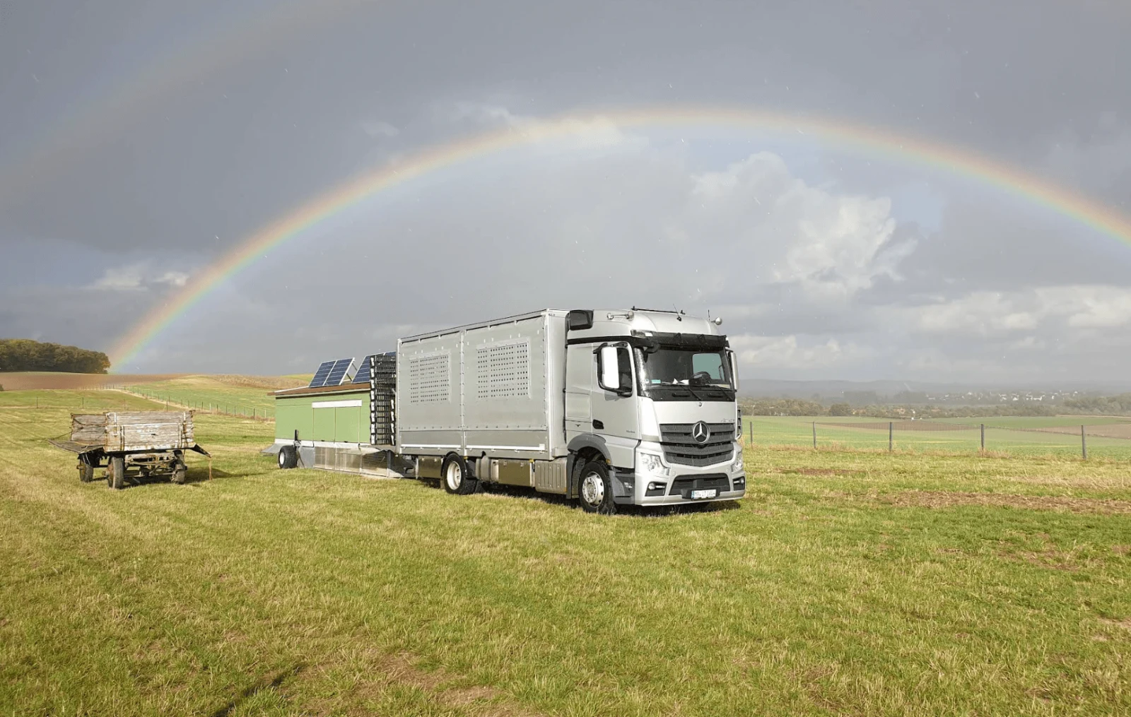 Bundesweite Junghennen-Lieferung mit Mercedes-LKW unter Regenbogen